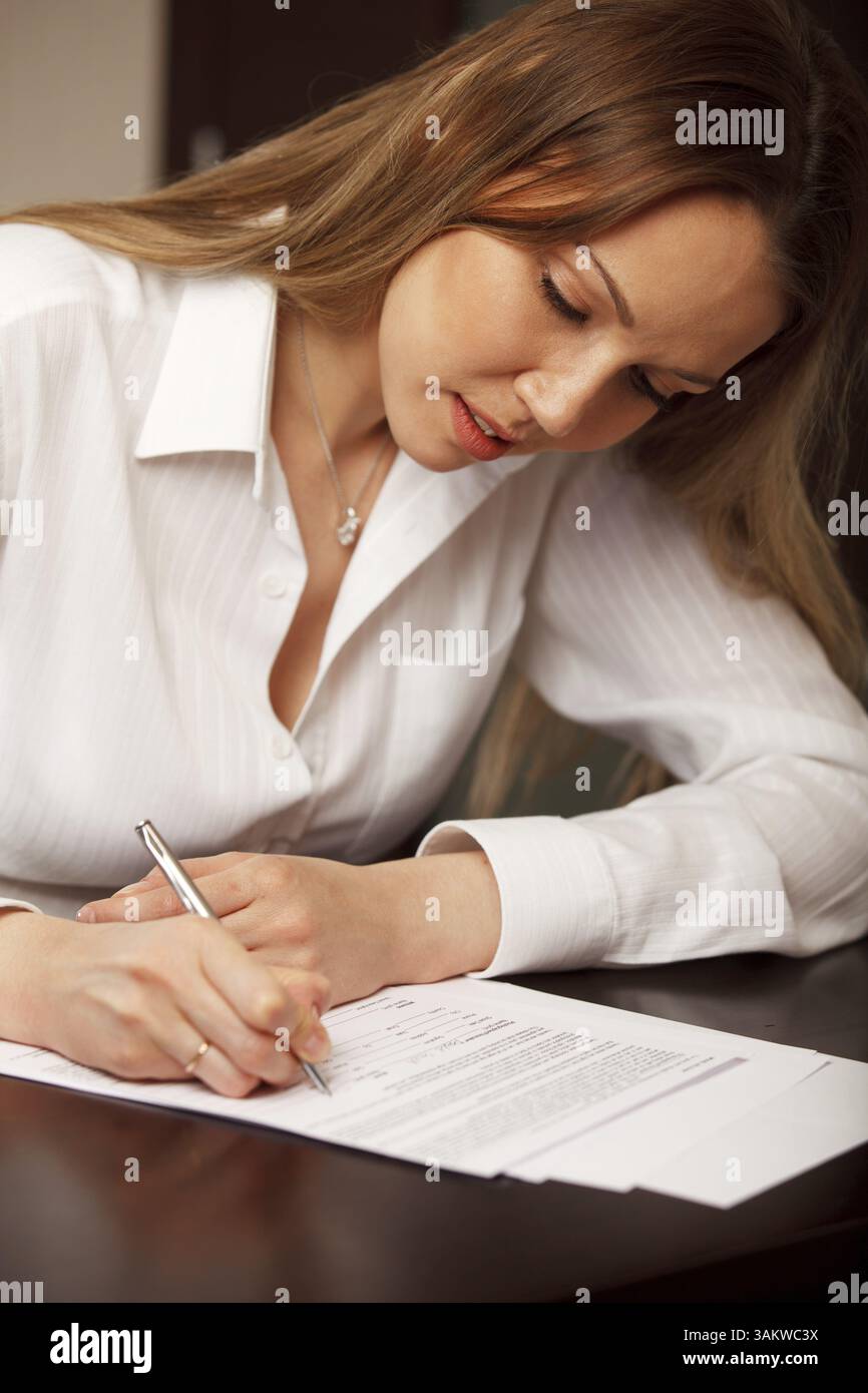 Attractive young woman signing contract Stock Photo - Alamy