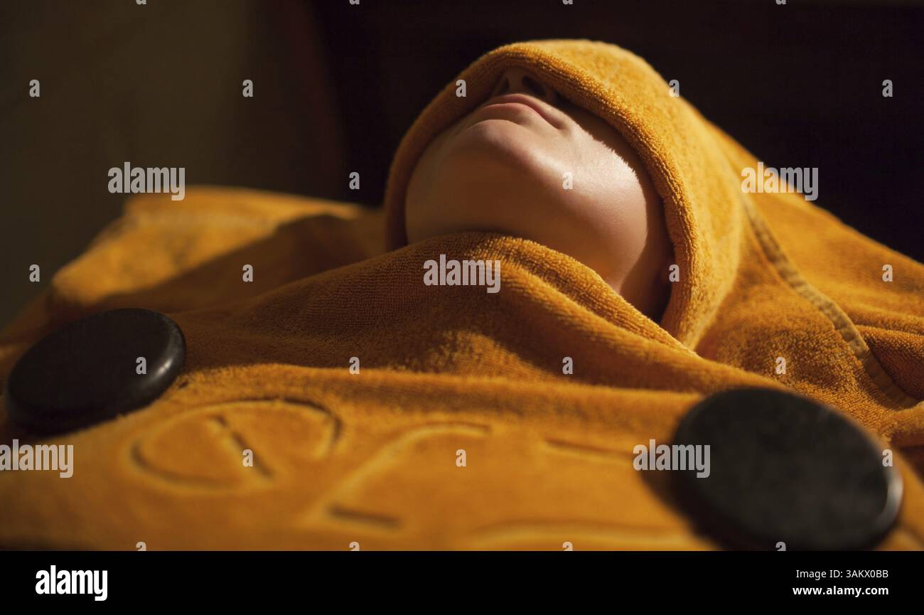 Relaxed woman at beauty treatment salon. She getting body and face hot towel therapy Stock Photo