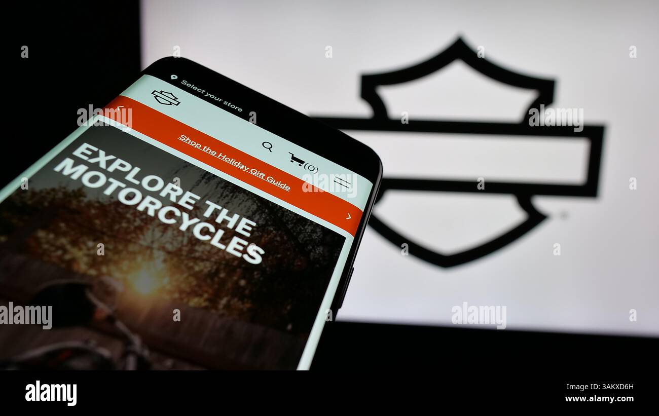Stuttgart, Germany - 11-26-2024: Mobile phone with website of US motorcycle company Harley-Davidson Inc. on screen in front of business logo. Stock Photo