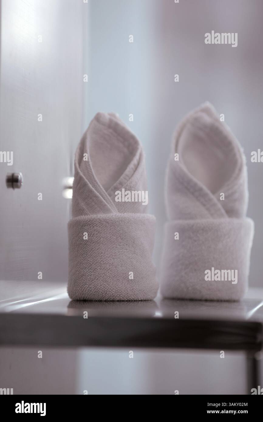 A close up of two rolled up white towels in a minimalistic interior Stock Photo