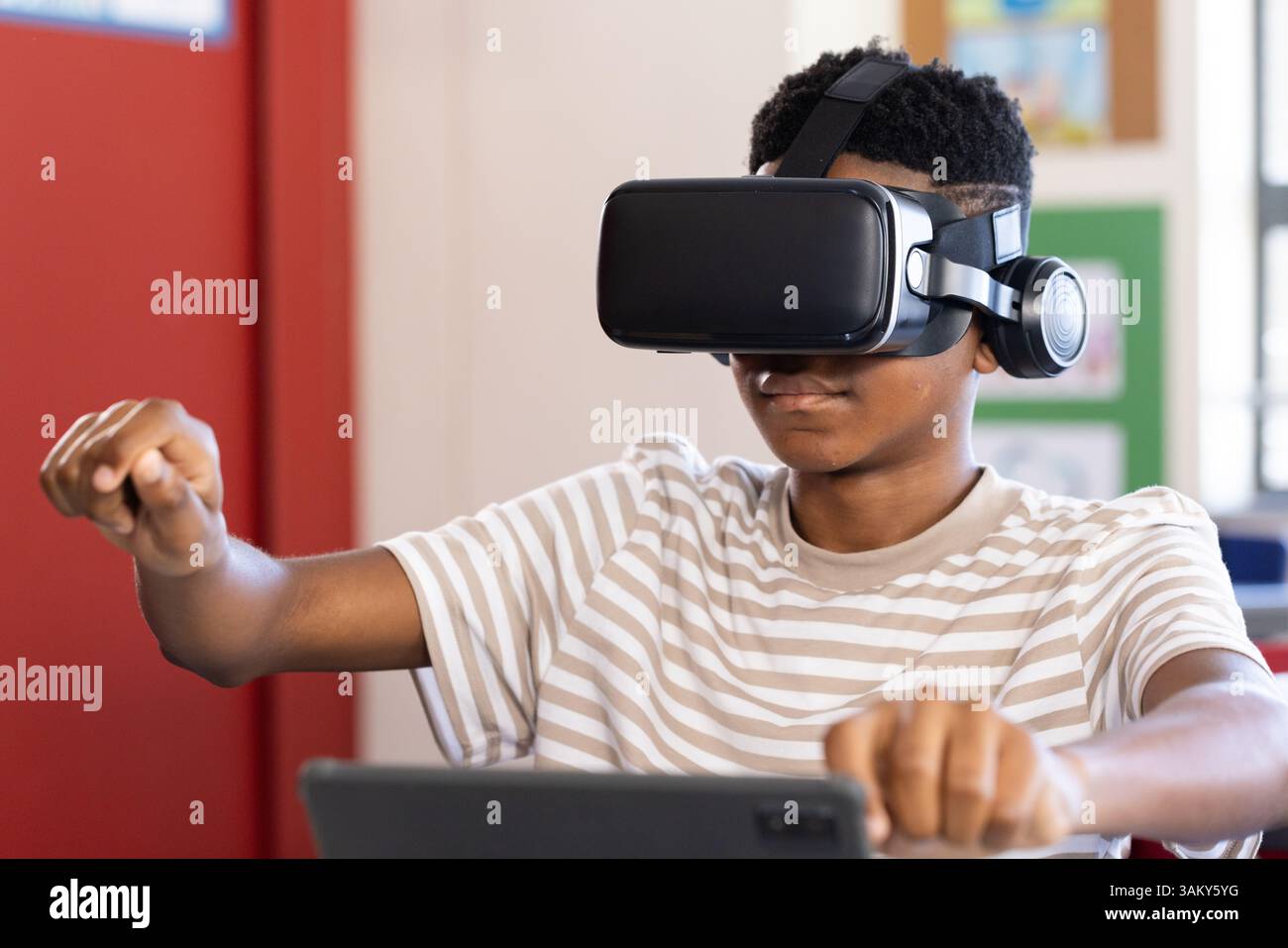 Using VR headset, boy in school engaging with virtual reality experience Stock Photo