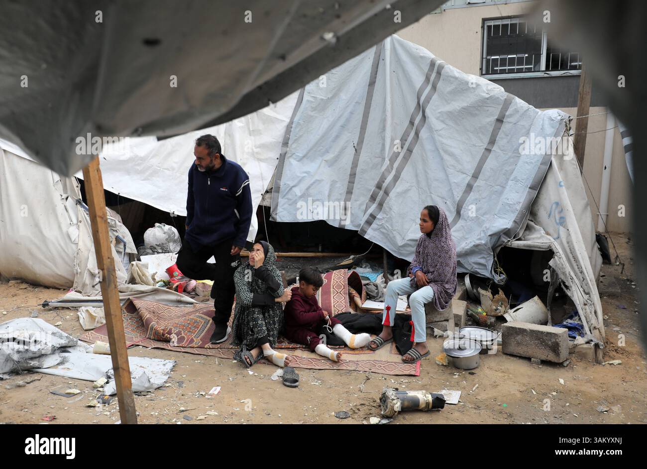 A displaced Palestinian family sits next to their tent, which was ...