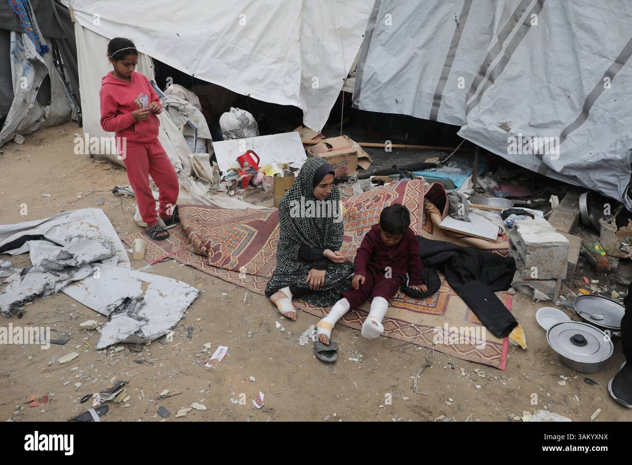 A displaced Palestinian family sits next to their tent, which was ...