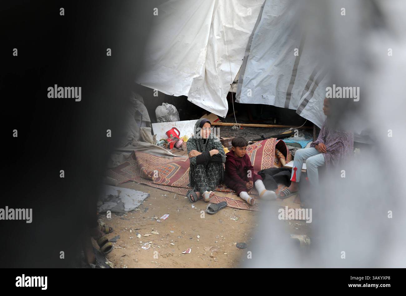 A displaced Palestinian family sits next to their tent, which was ...