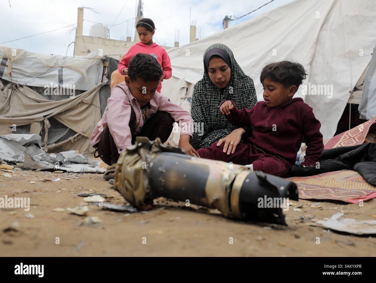 A displaced Palestinian family sits next to their tent, which was ...