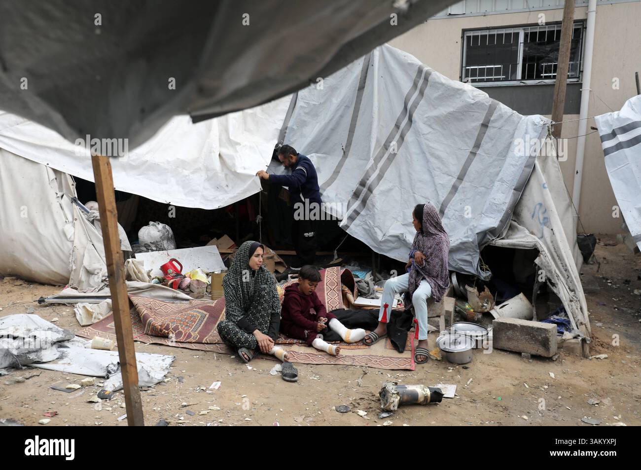A displaced Palestinian family sits next to their tent, which was ...