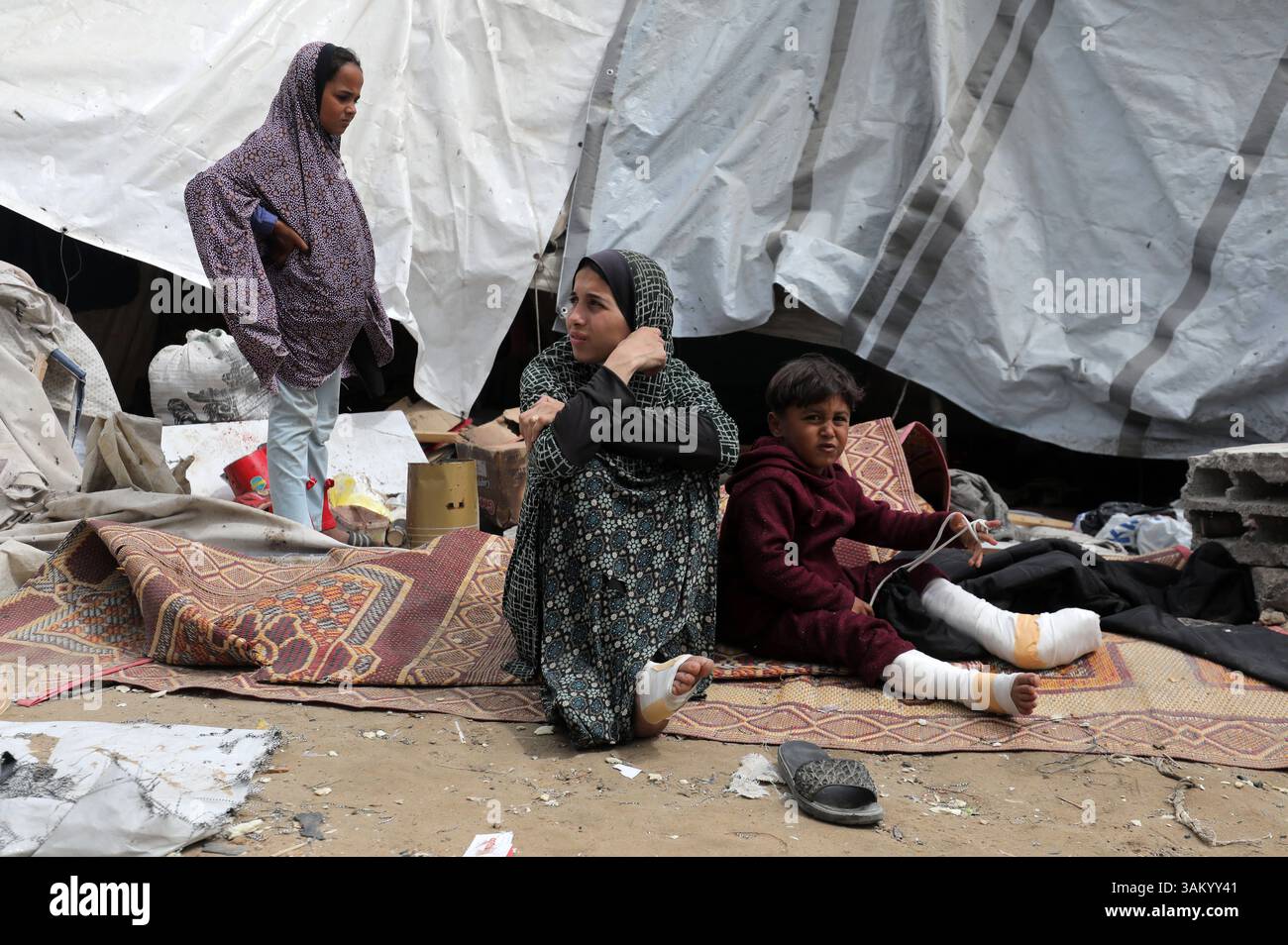 A displaced Palestinian family sits next to their tent, which was ...