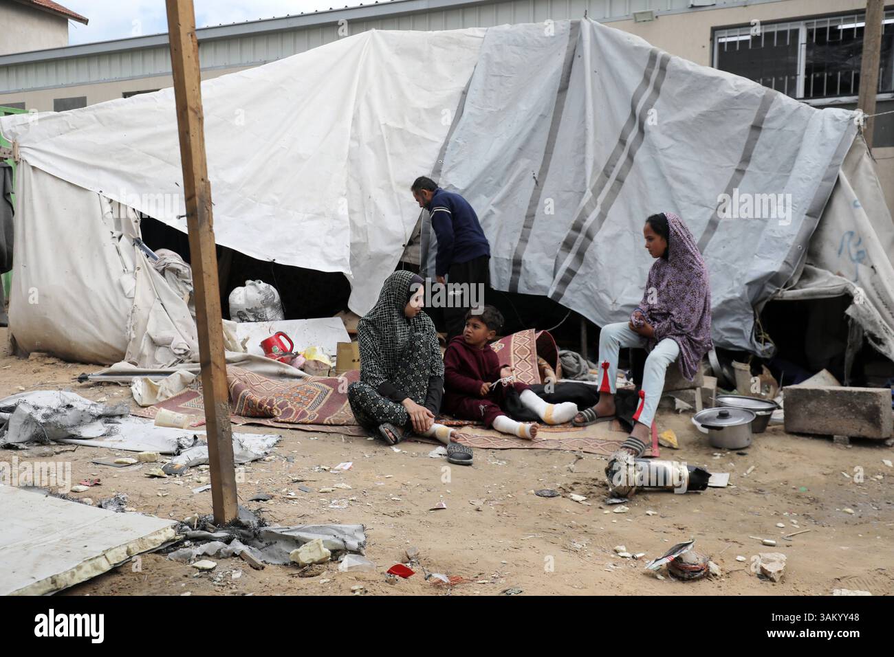 A displaced Palestinian family sits next to their tent, which was ...