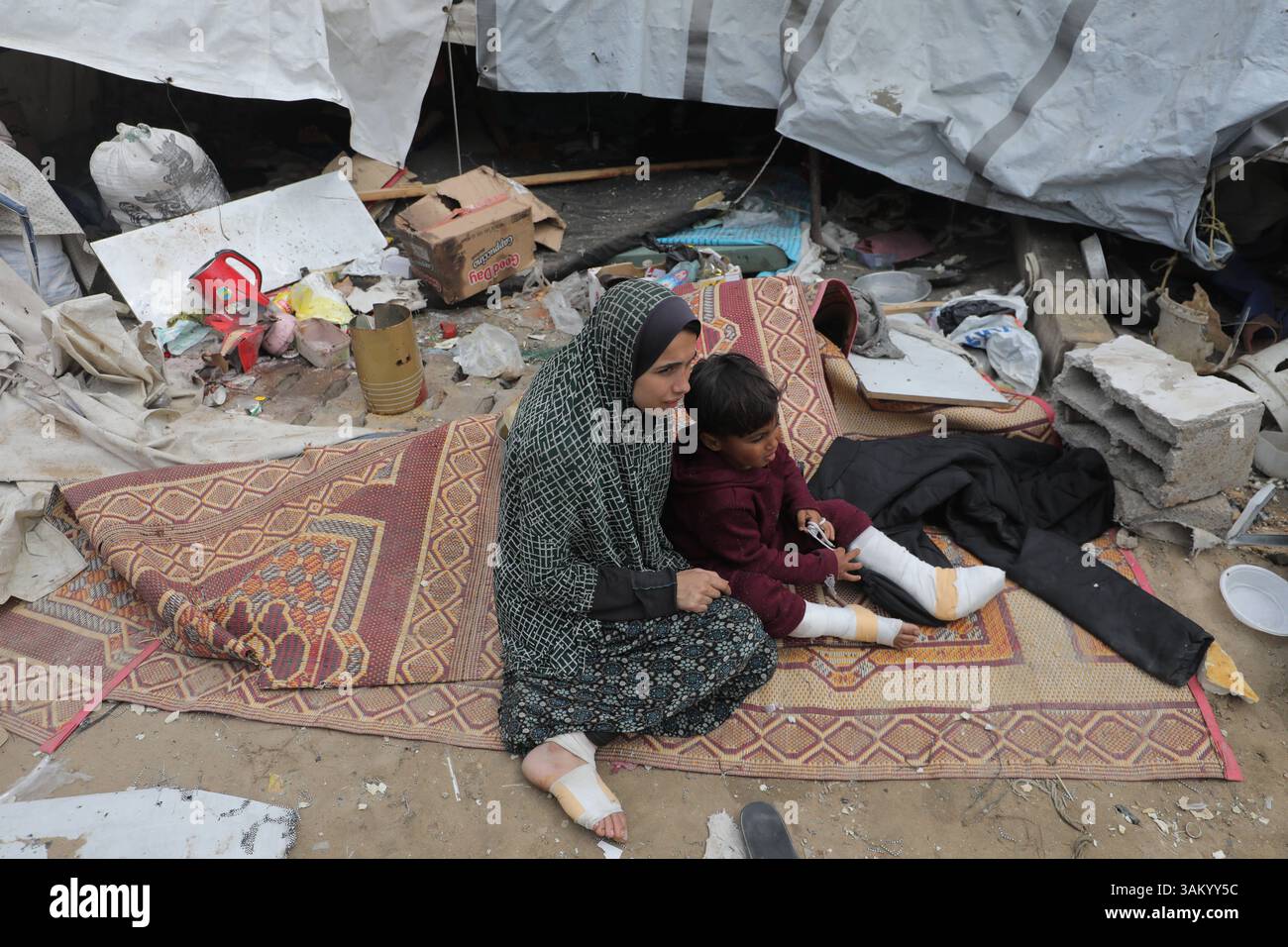 A displaced Palestinian family sits next to their tent, which was ...