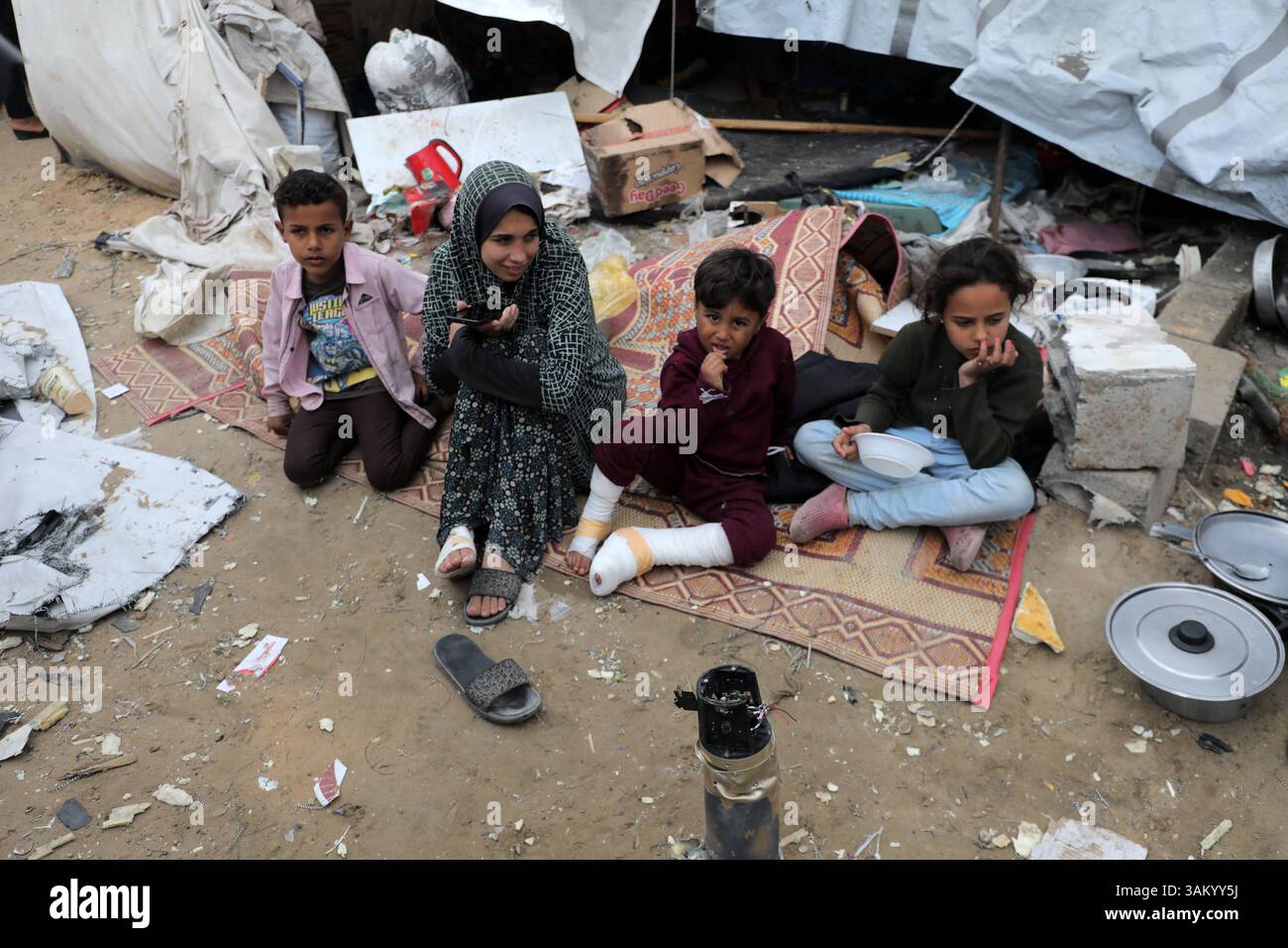A displaced Palestinian family sits next to their tent, which was ...