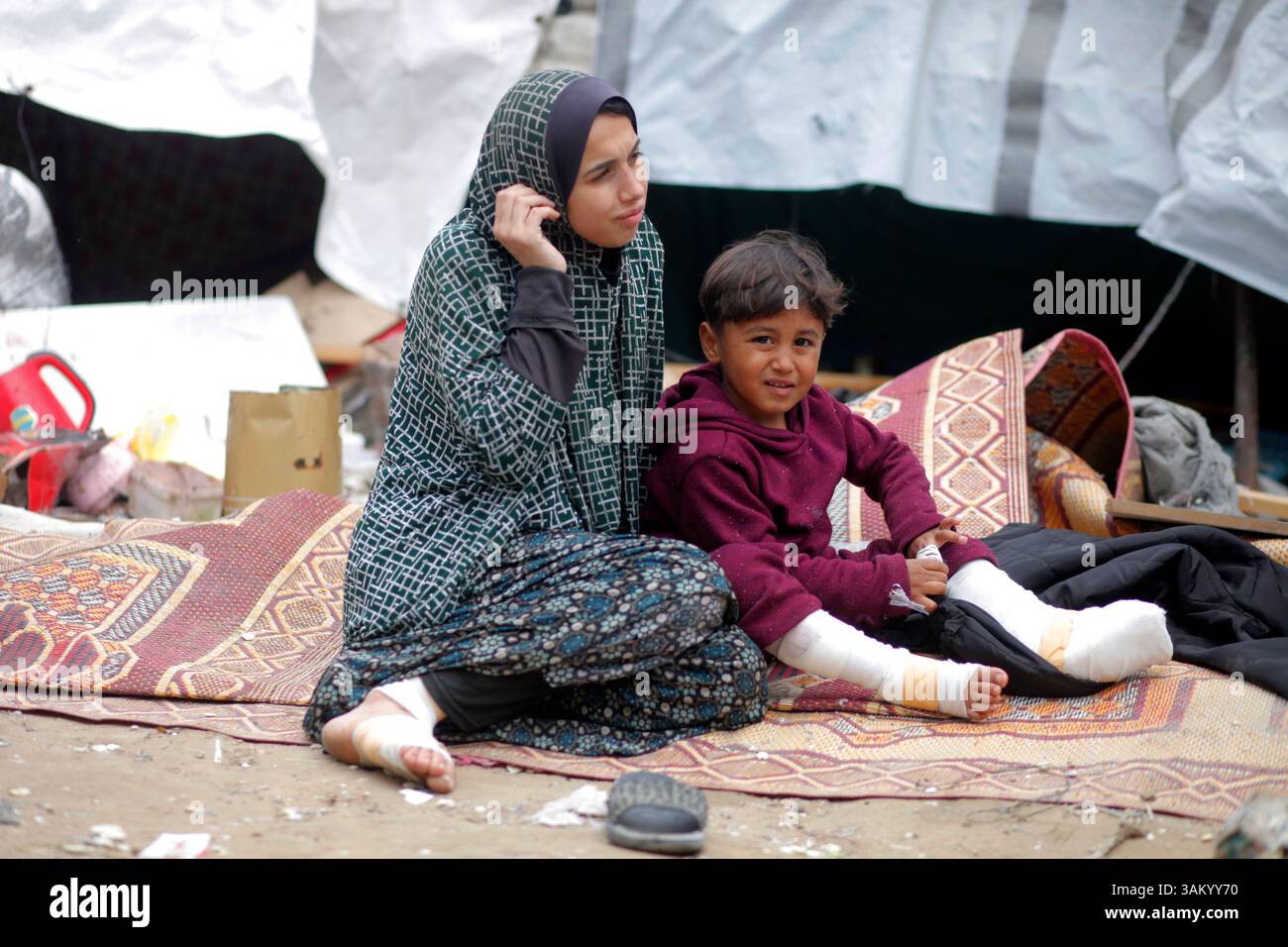 A displaced Palestinian family sits next to their tent, which was ...