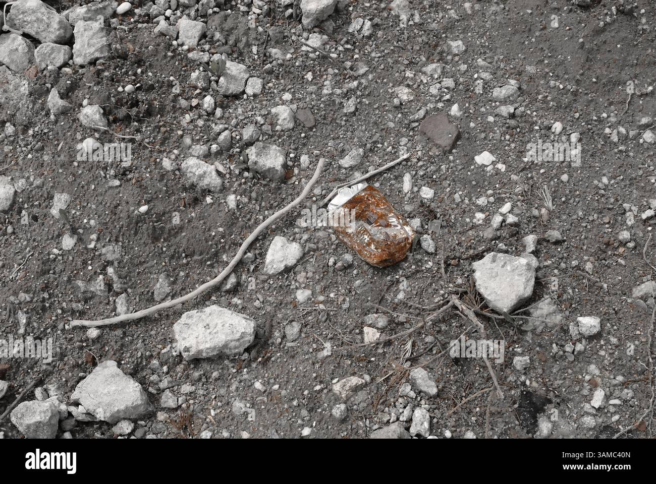 A discarded machine part lies in the gravel, rusty and marked by time - a symbol of transience, technology and industrial decay. Stock Photo