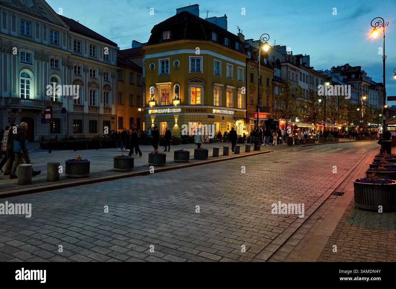 Busy city street at night with people walking and cars driving. The ...