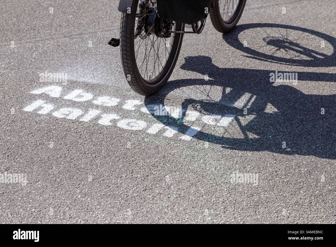 the lettering 'Keep your distance' is sprayed in white paint on the asphalt Stock Photo
