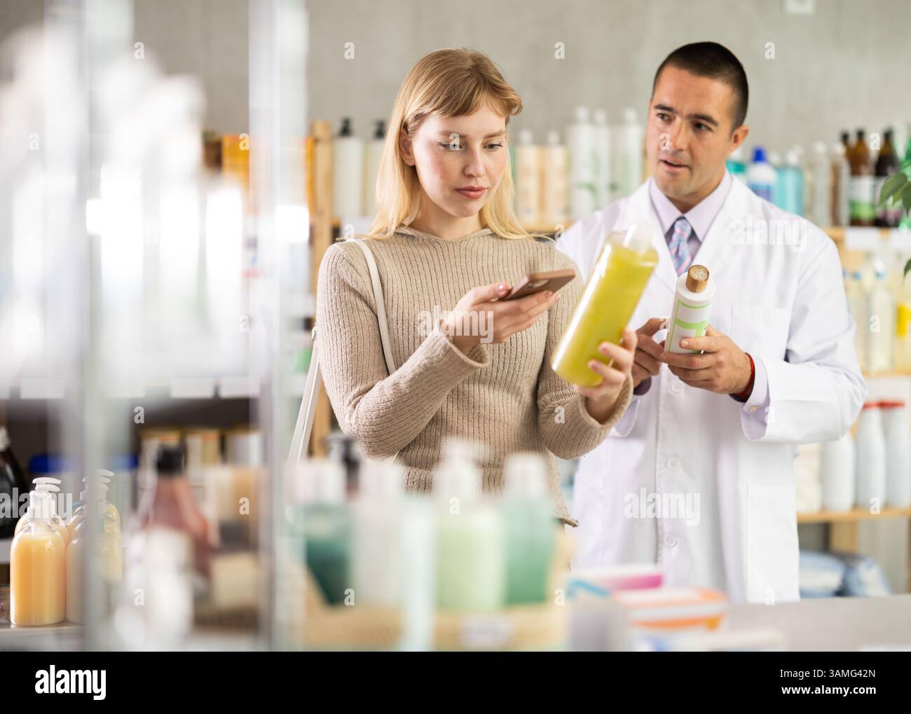 Young woman scanning QR-code on shampoo while pharmacist offering Stock ...