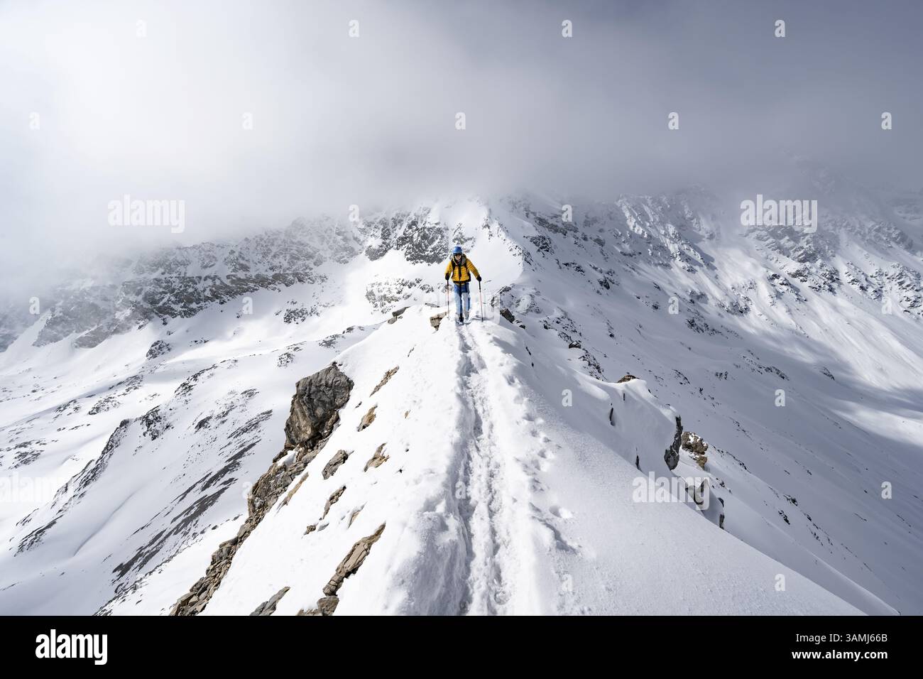 Mountaineer climbing up the narrow ridge of Piz Laviner, view of wintry ...