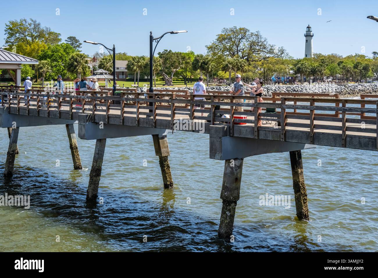 People fishing from the St. Simons Island Pier with the lighthouse in ...