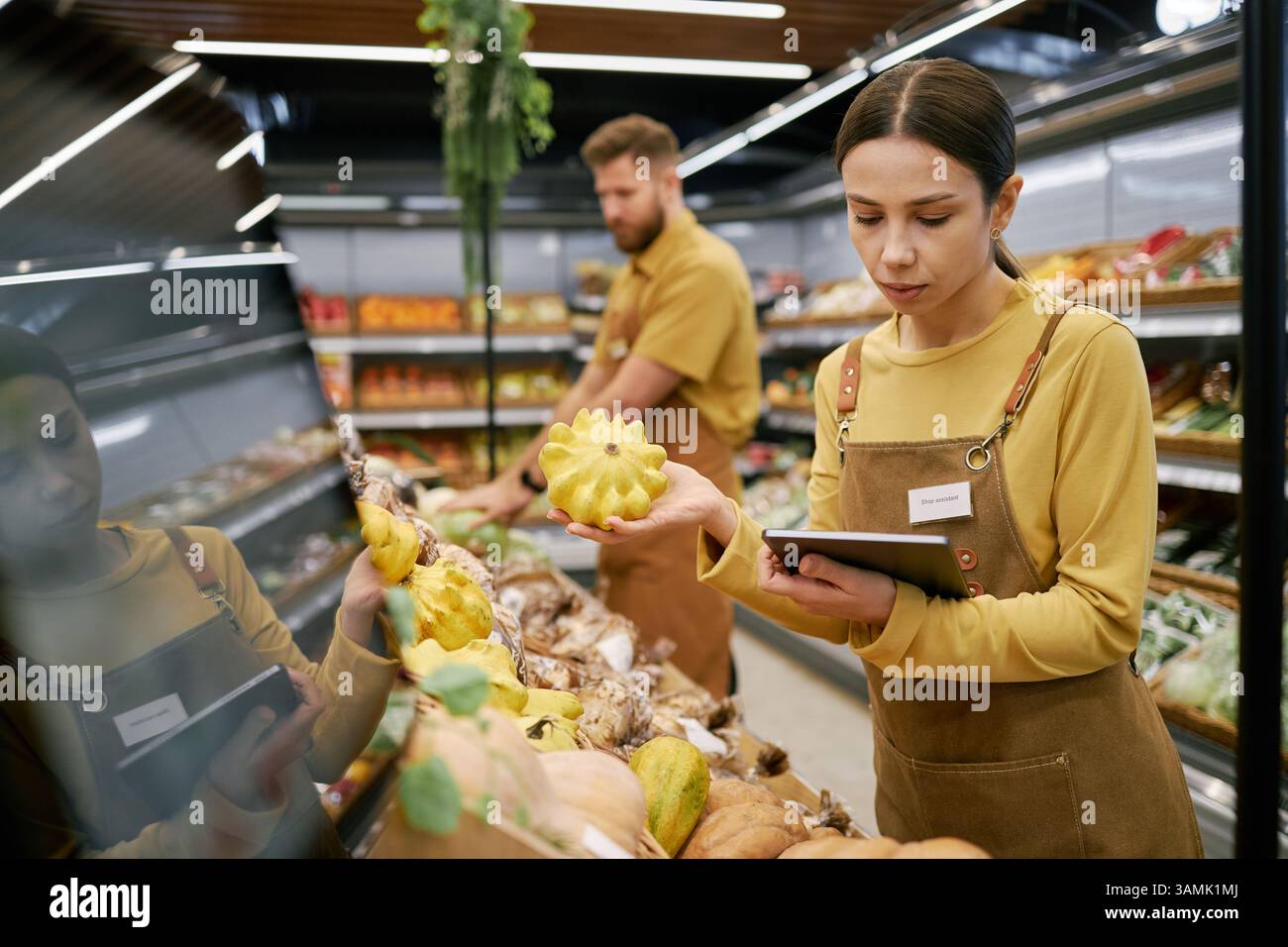 Grocery store worker inspecting yellow produce while holding a digital ...
