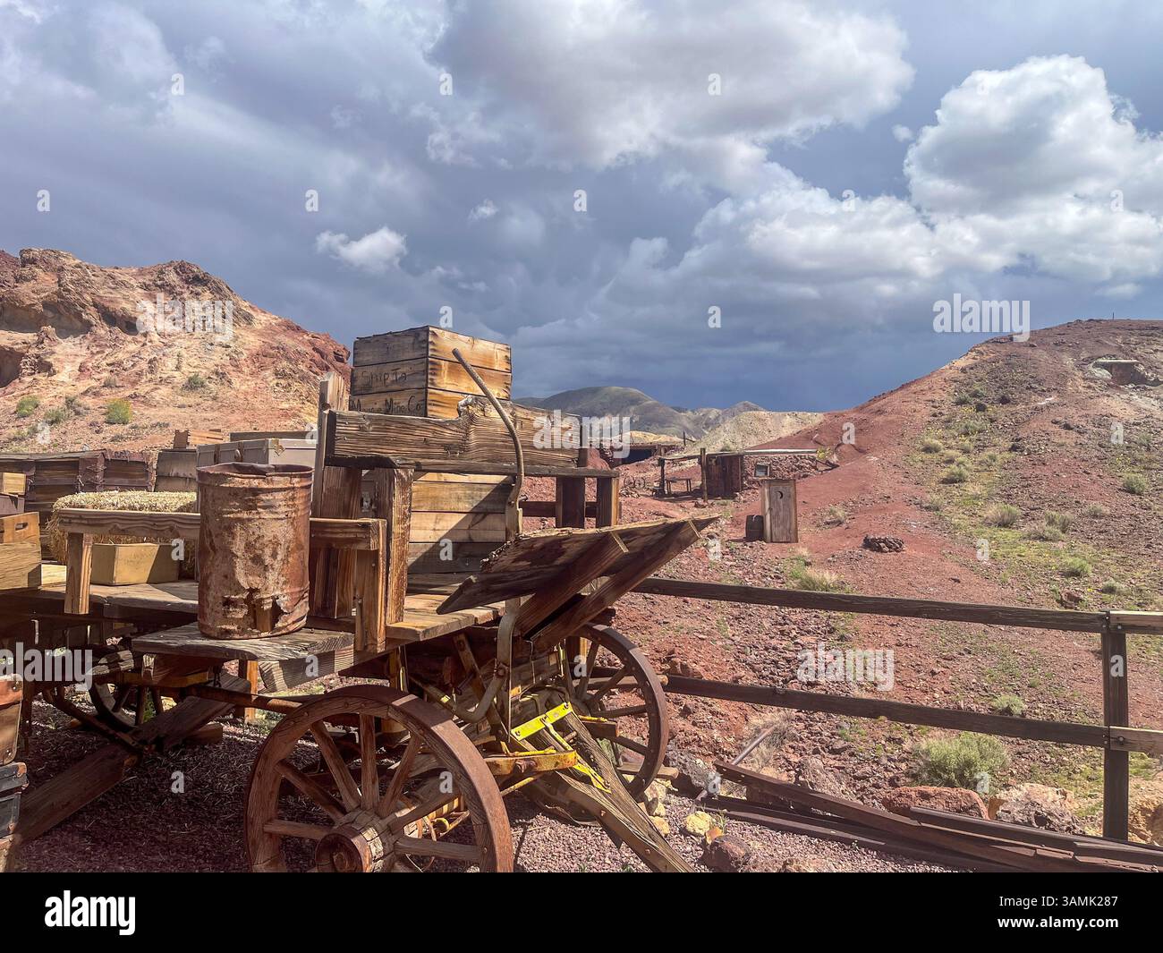 Wooden wagon in mining town surrounded by hills and rugged terrain under stormy sky. - Smartphone Captured Stock Image