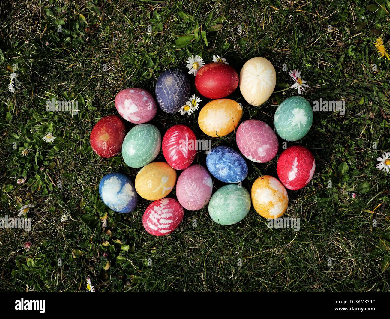 Colorful Easter eggs dyed with store-bought colors. Plants and nets create delicate patterns on the vibrantly colored eggshells. Stock Photo