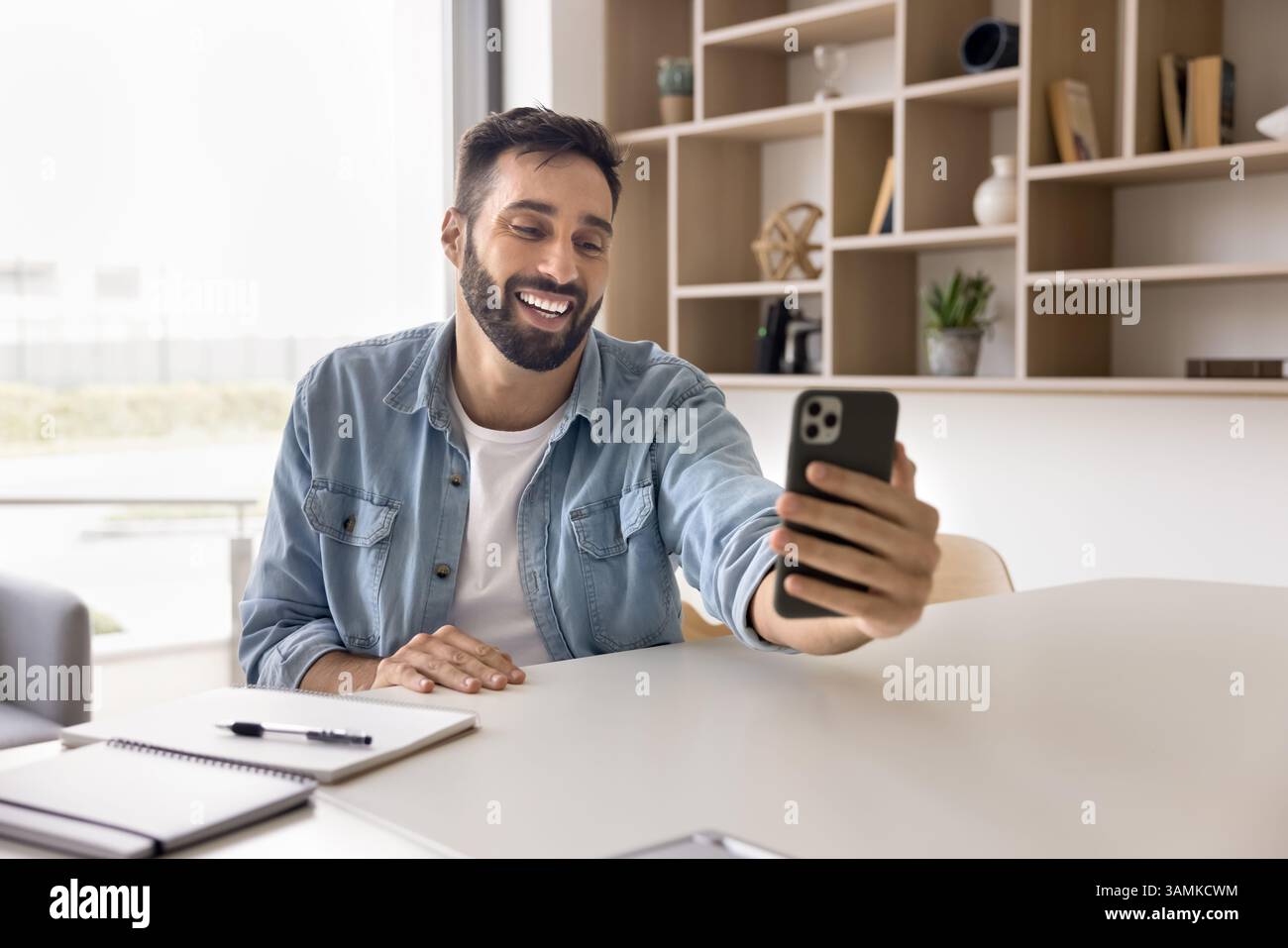 Smiling young businessman enjoy talking by videocall on cellphone Stock Photo