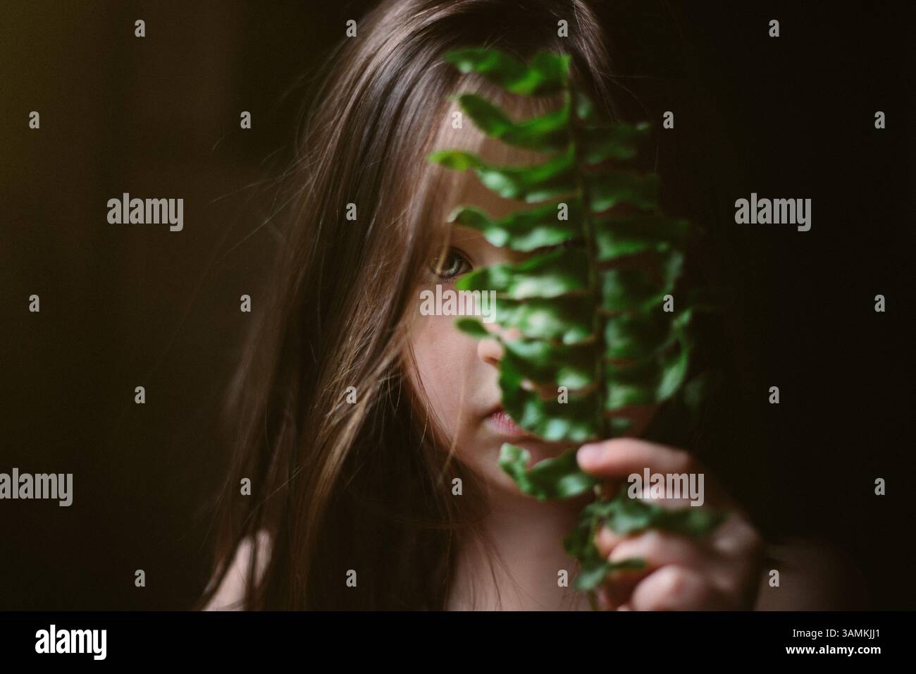 Girl holding fern leaf in front of face Stock Photo - Alamy