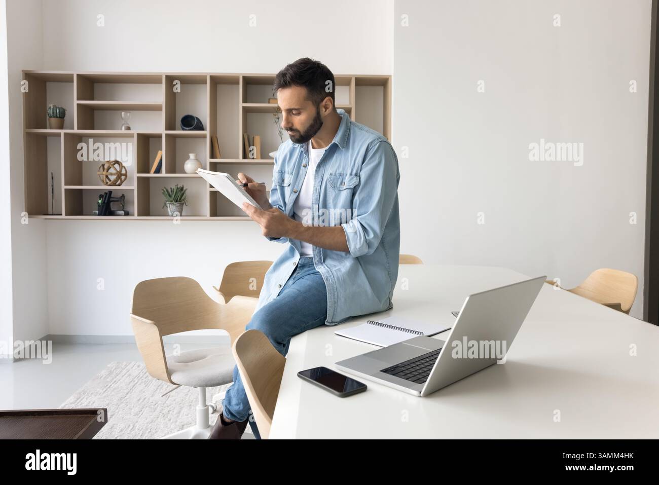 Young man remote worker reviewing paper documents at home office Stock Photo