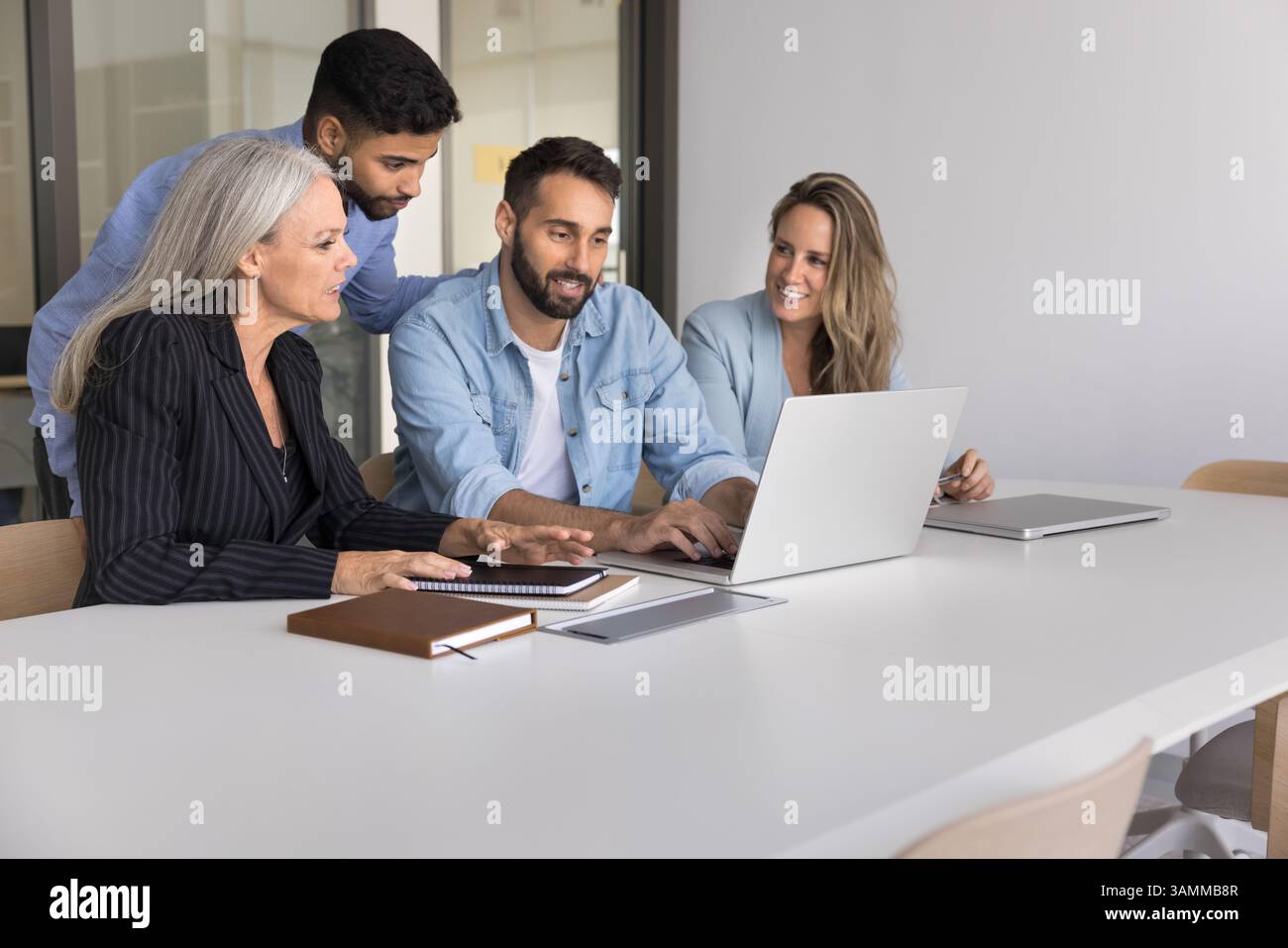 Skilled male mentor explain work on notebook to interns group Stock Photo