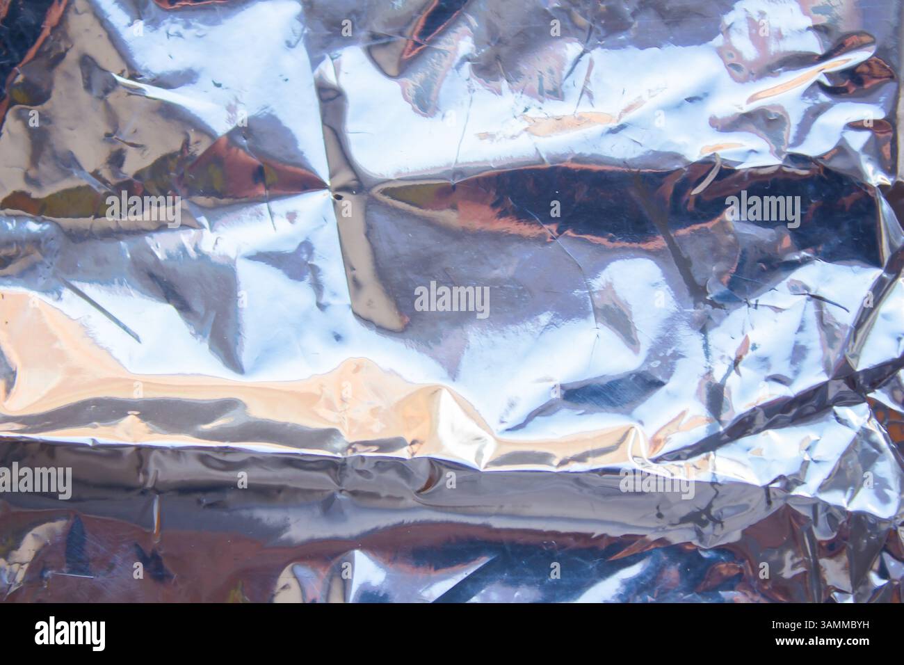 Crumpled reflective shiny gift wrapping material texture background Stock Photo