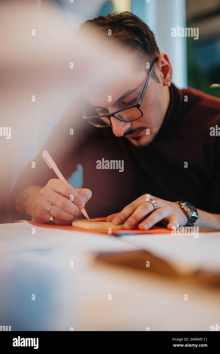 Man Focused on Writing Notes During a Professional Brainstorming Session Stock Photo