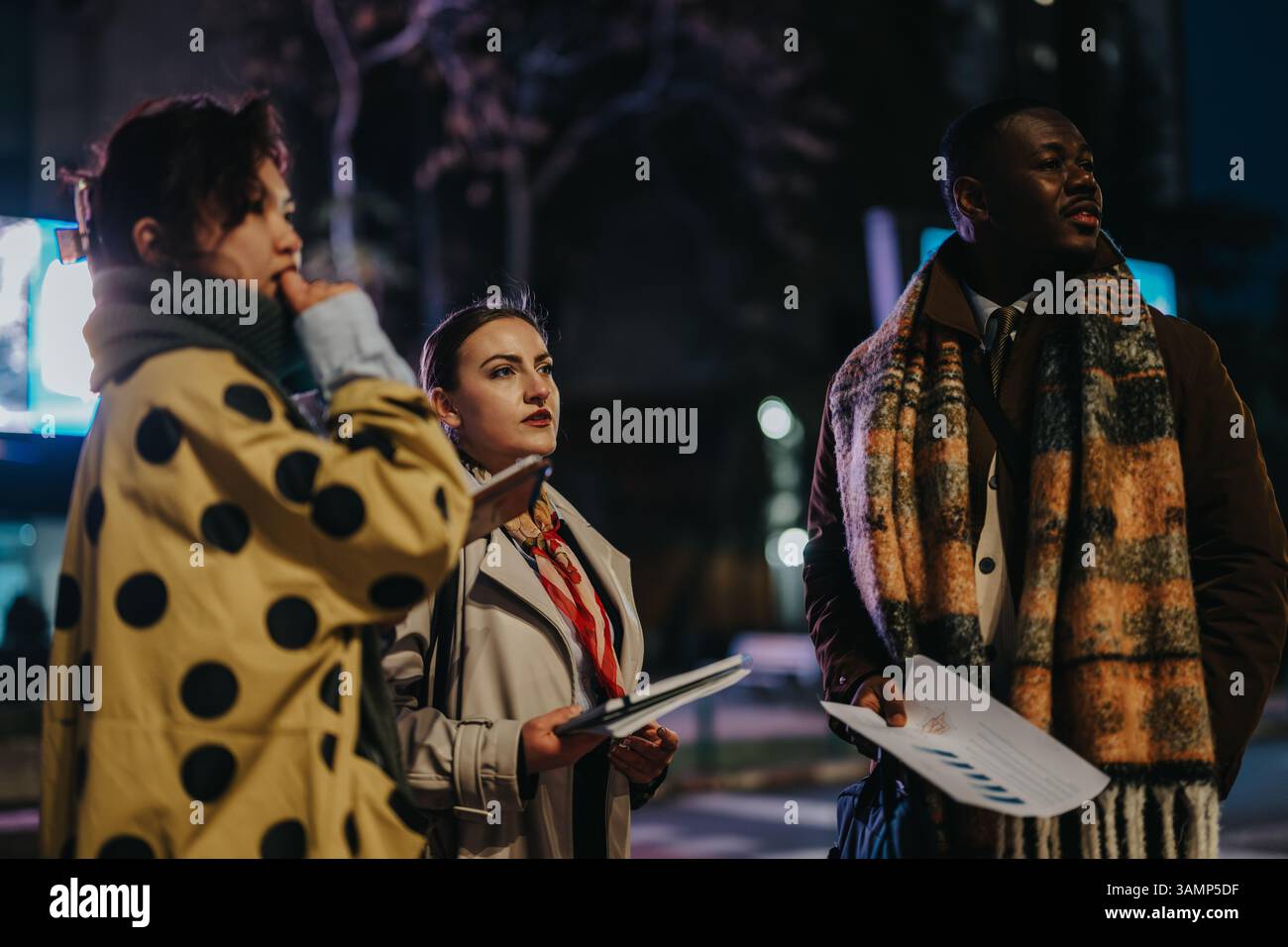 Multiracial people collaborating outdoors during evening while discussing and reviewing documents Stock Photo