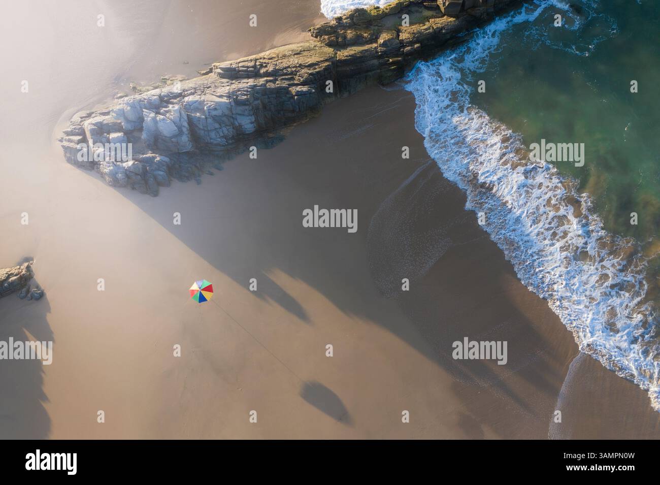 Aerial view of tranquil beach with umbrella, rocks, and clear water, Wilderness Beach, Western Cape, South Africa. Stock Photo