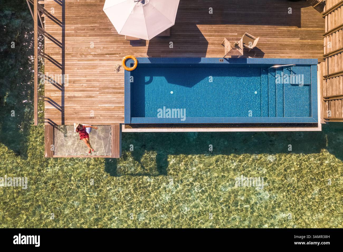 Aerial view of a woman relaxing along the swimming pool in a luxury ...