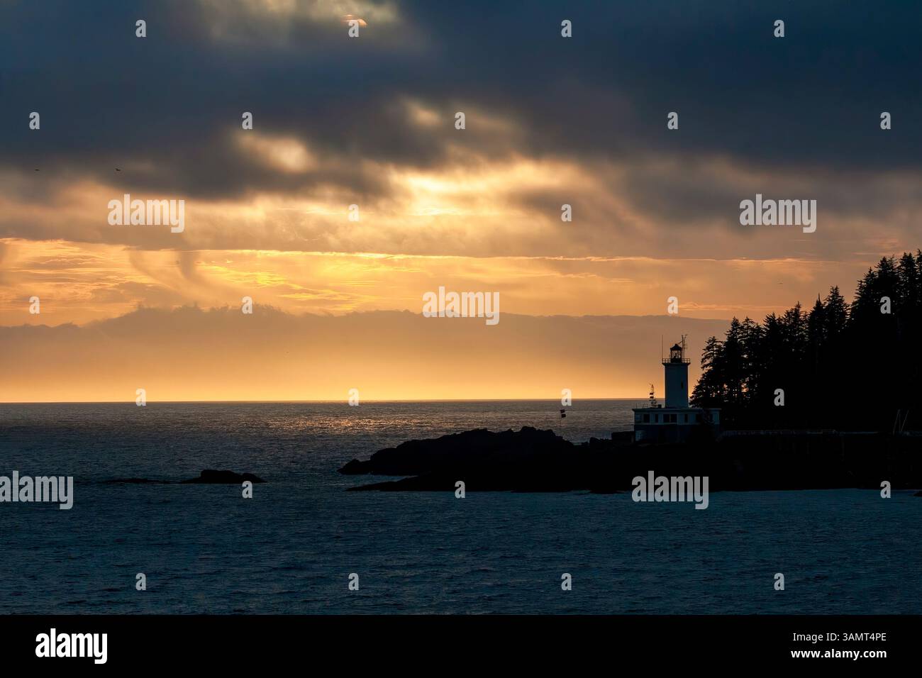Sunset behind Lighthouse on the rugged coastline in Alaska, waters of the Inside Passage Stock Photo