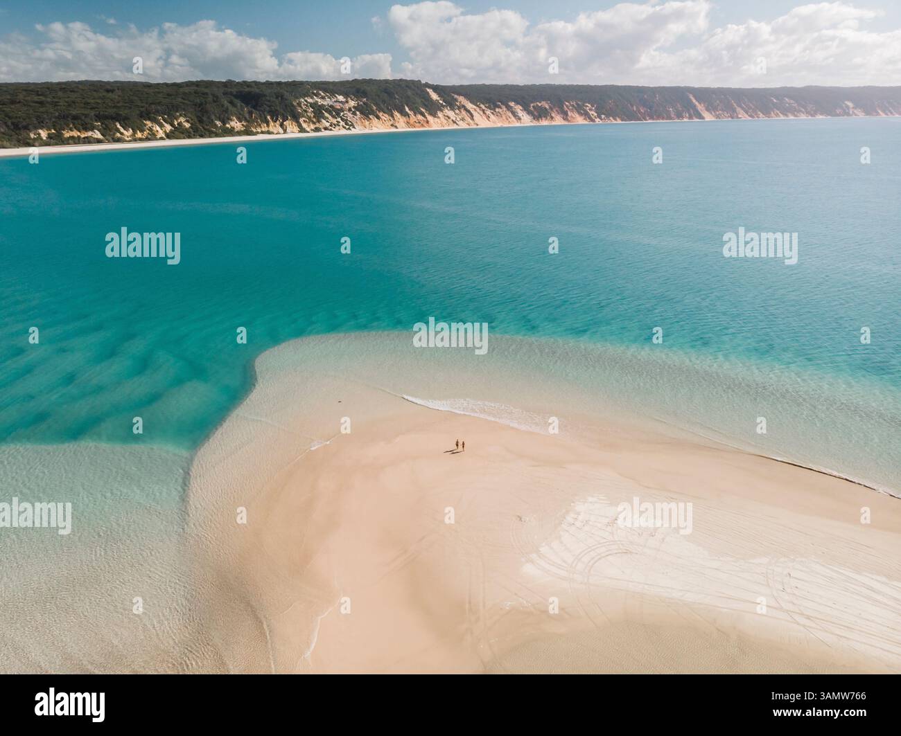 Aerial view of a couple walking on the beach with the coloured sand of ...