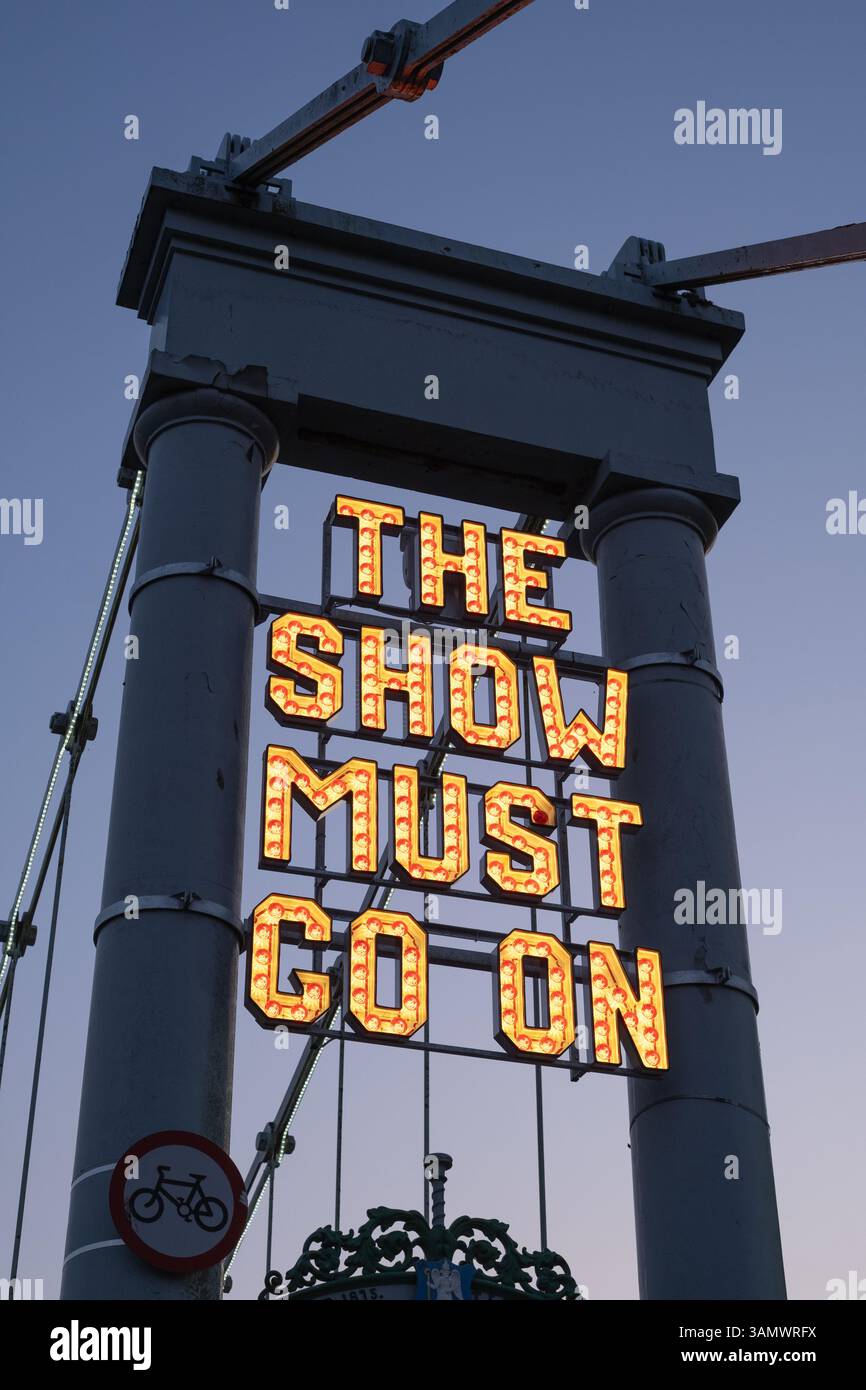 Neon sign 'The Show Must Go On' installed by The Stove Network over the Dumfries Suspension Bridge, inspired by the historic Rood Fair. Stock Photo