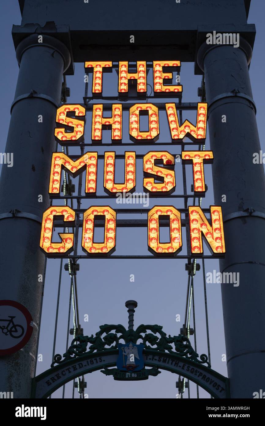 Neon sign 'The Show Must Go On' installed by The Stove Network over the Dumfries Suspension Bridge', inspired by the historic Rood Fair. Stock Photo