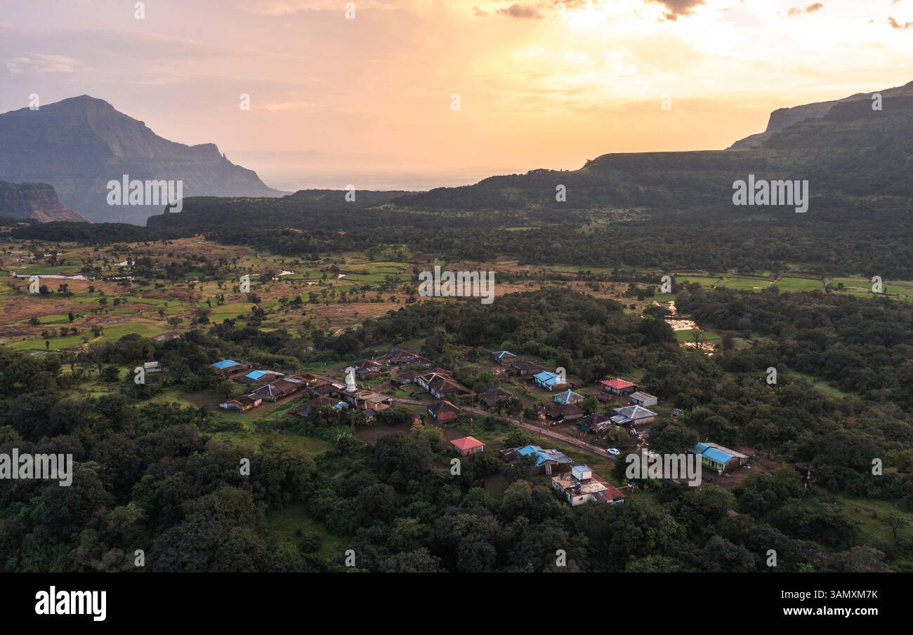 Aerial view of serene village, majestic mountains, lush forest, and ...