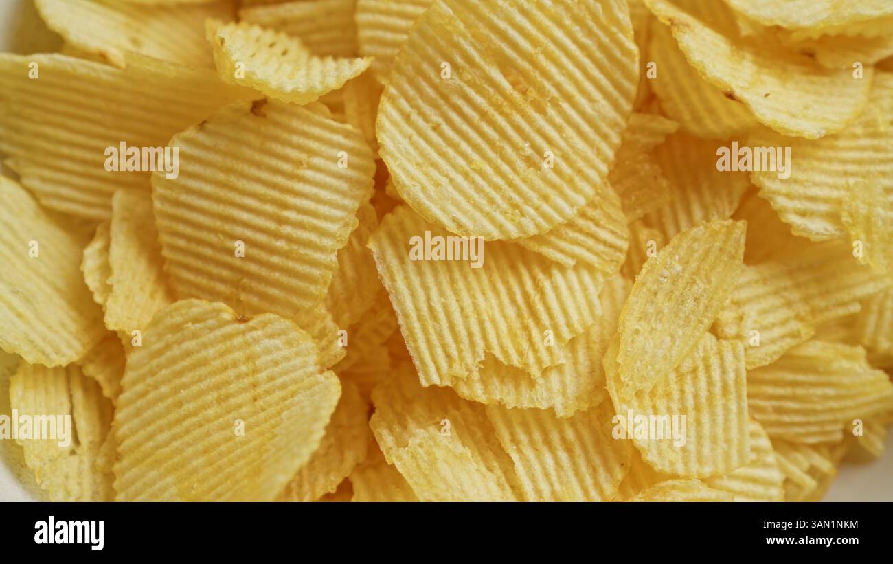 Close-up shot of fresh, crispy potato chips arranged in a pile showcasing texture and golden brown color. Stock Photo