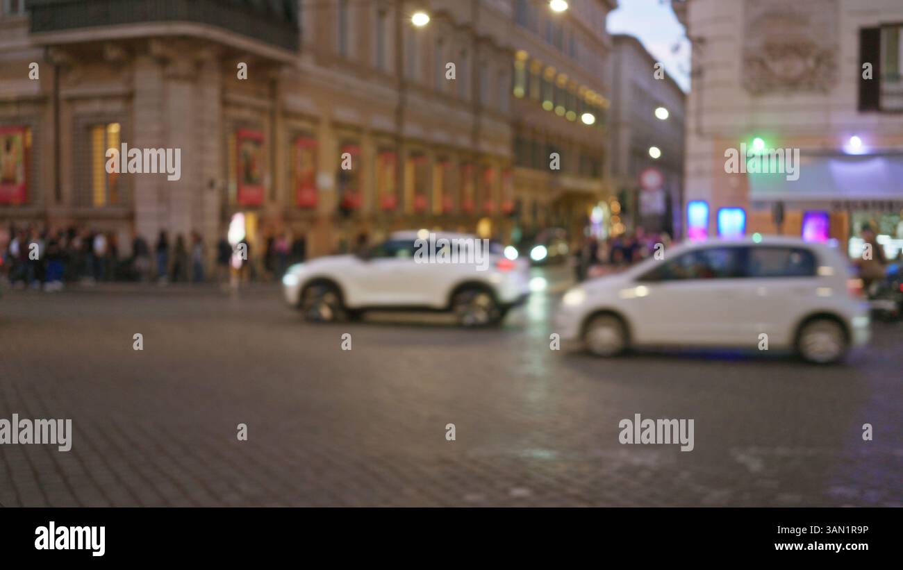 Night street scene in rome with blurred cars and blurred pedestrians ...