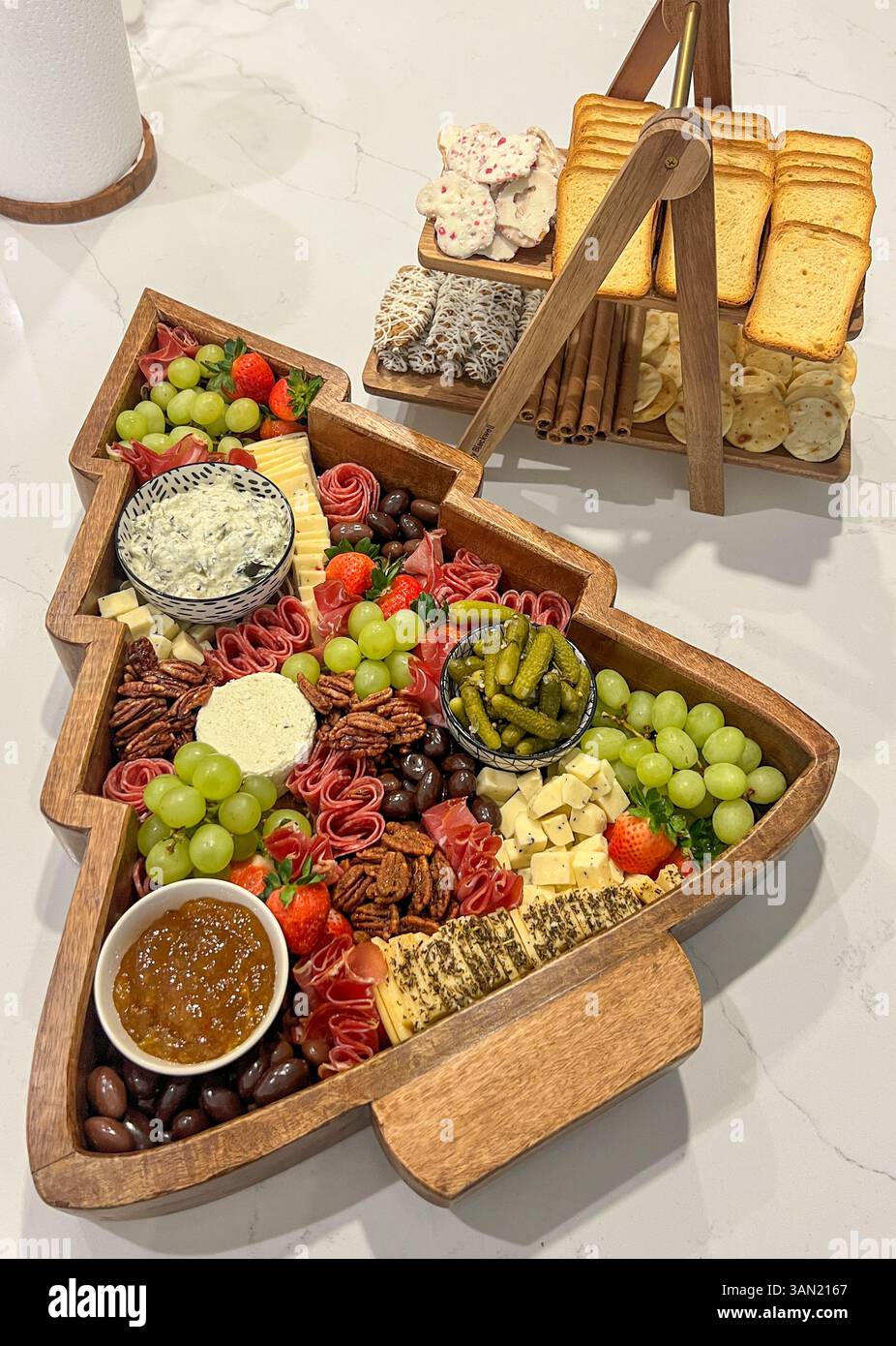 A festive holiday charcuterie spread with meats, cheeses, fruits, dips, and sweet treats served in a tree-shaped tray, perfect for seasonal entertaini - Smartphone Captured Stock Image