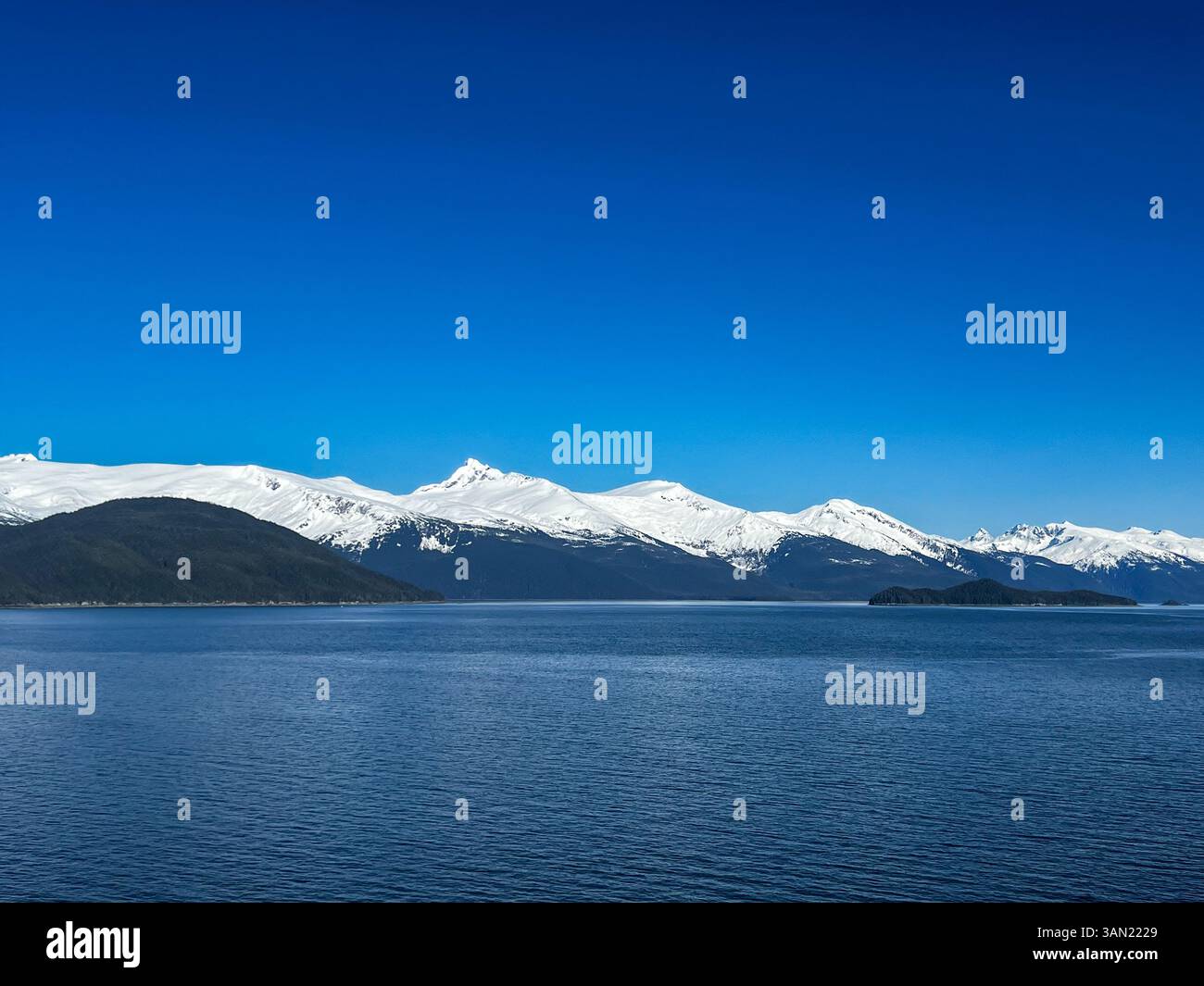 A breathtaking view of snow-covered peaks rising above deep blue waters, showcasing the untouched beauty of the Arctic landscape. A perfect moment in - Smartphone Captured Stock Image