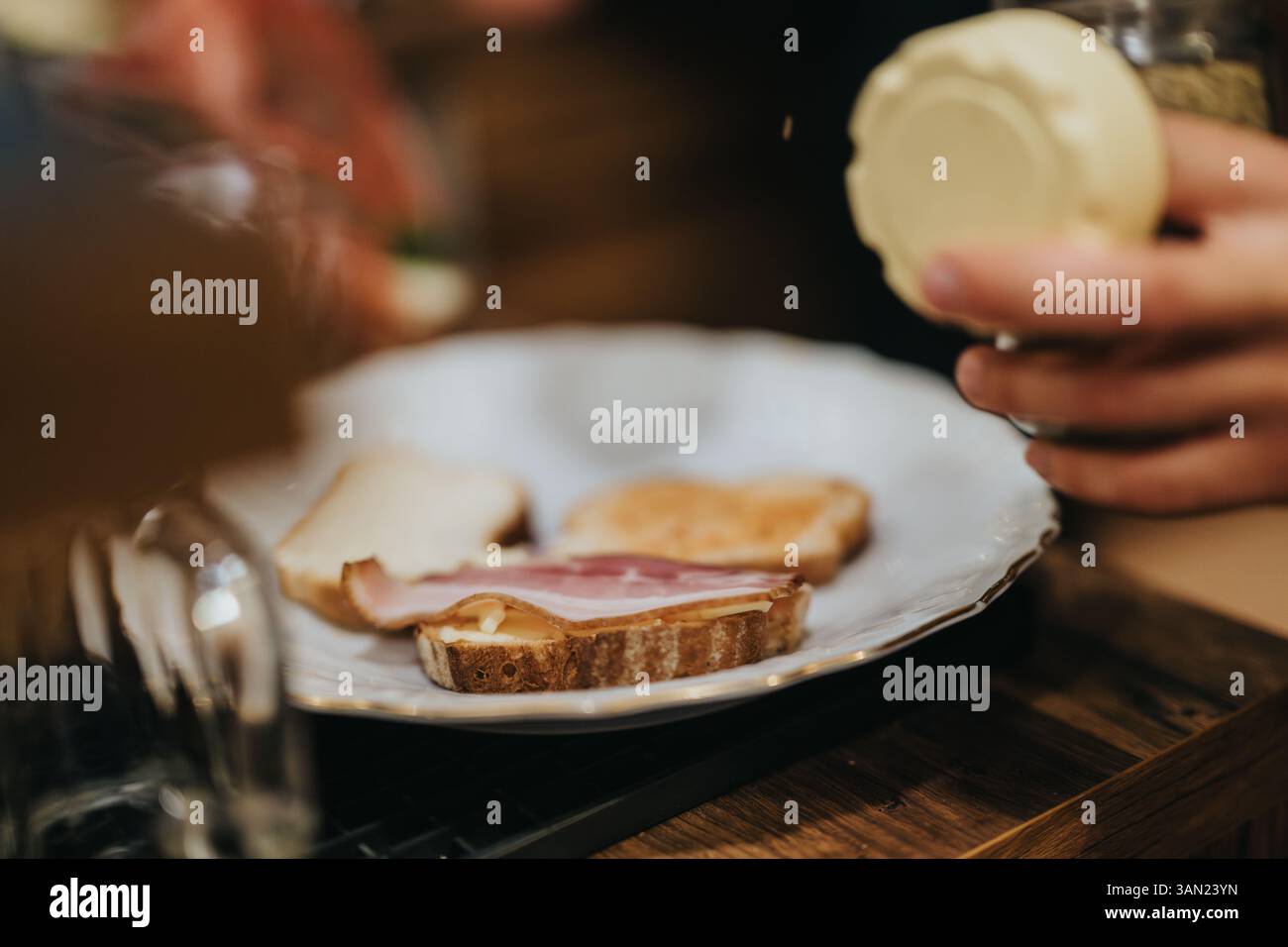 Preparing bread slices with toppings during culinary activity at a cozy kitchen setup Stock Photo