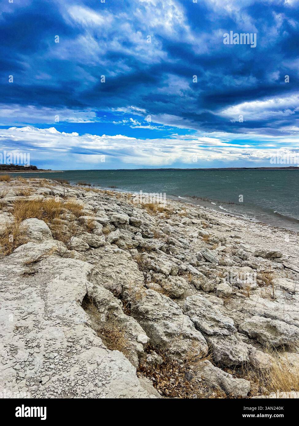 Dark clouds gather over the windswept shoreline, contrasting the rough limestone rocks and the restless waters below. - Smartphone Captured Stock Image