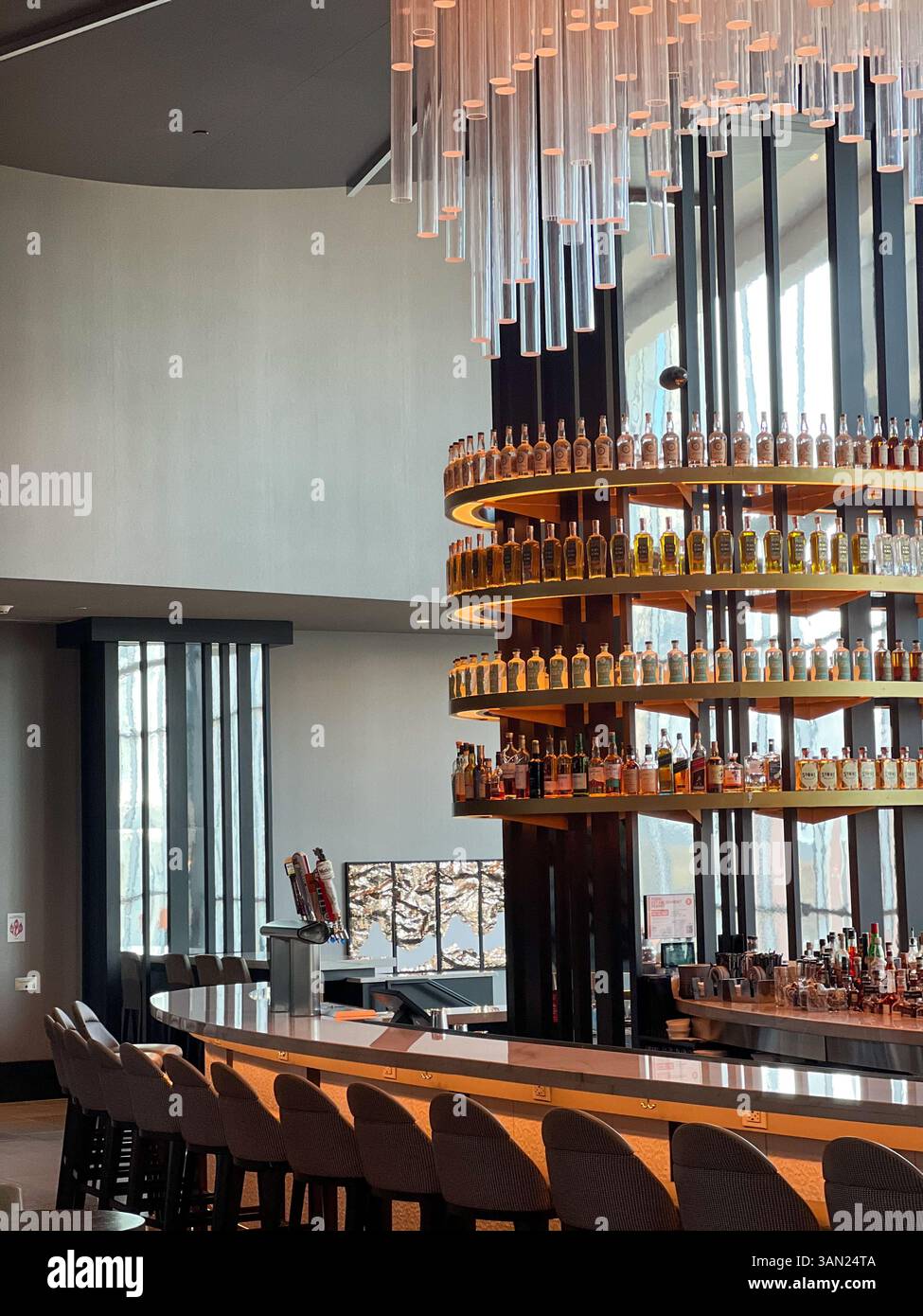 A stylish hotel bar featuring a glowing spiral bottle display and sleek seating, perfect for unwinding with a crafted cocktail in a contemporary setti - Smartphone Captured Stock Image