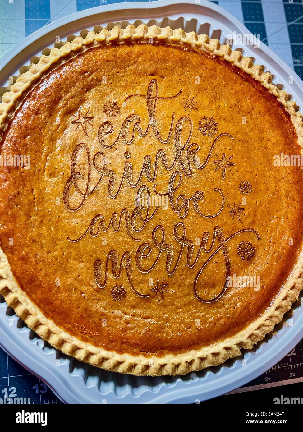 This festive pumpkin pie says it all—perfectly baked and beautifully etched with holiday cheer. A sweet reminder to eat, drink, and be merry. - Smartphone Captured Stock Image