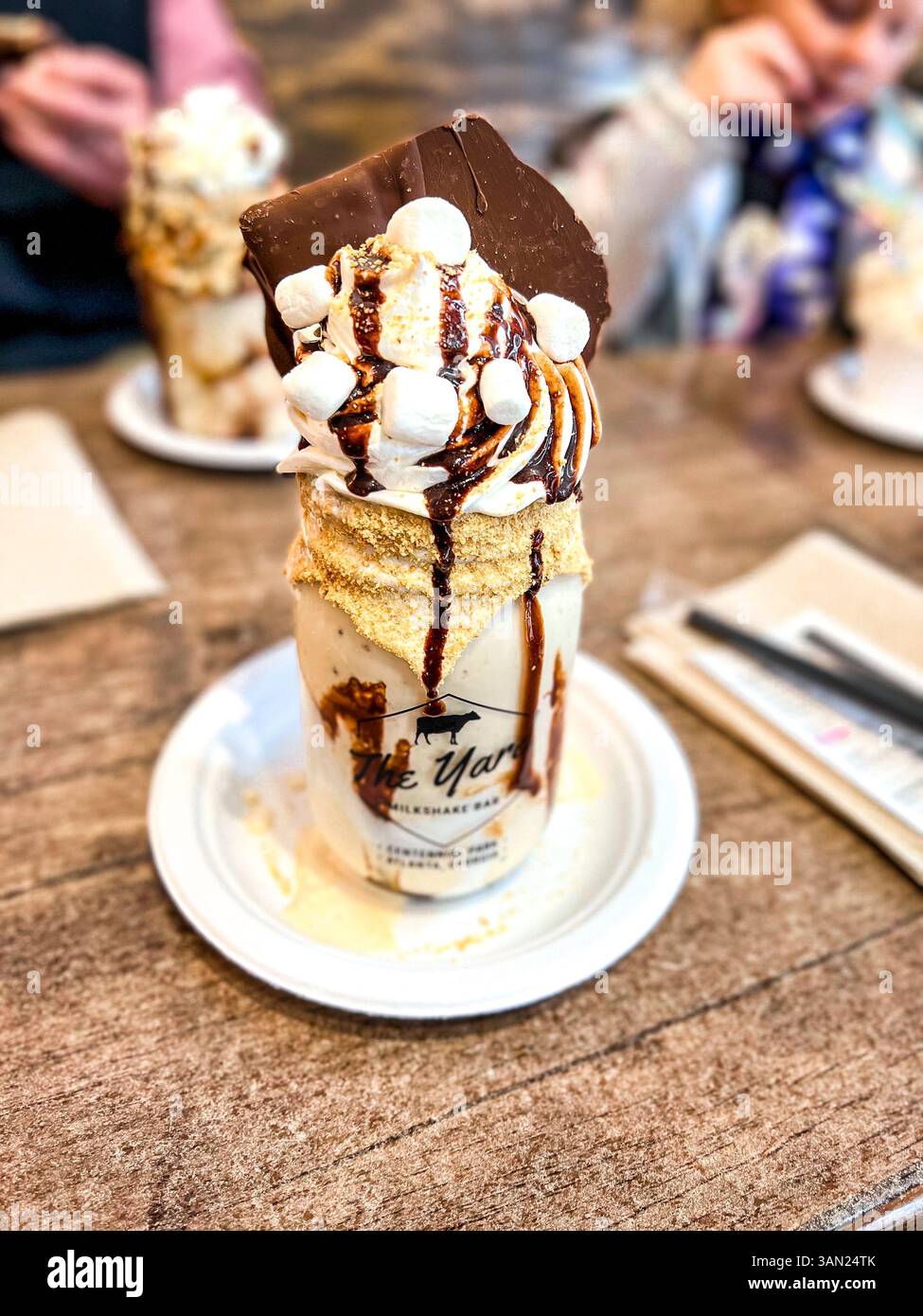 This towering s’mores milkshake from The Yard is a dessert lover’s dream—loaded with marshmallows, chocolate drizzle, and a giant chocolate square. - Smartphone Captured Stock Image