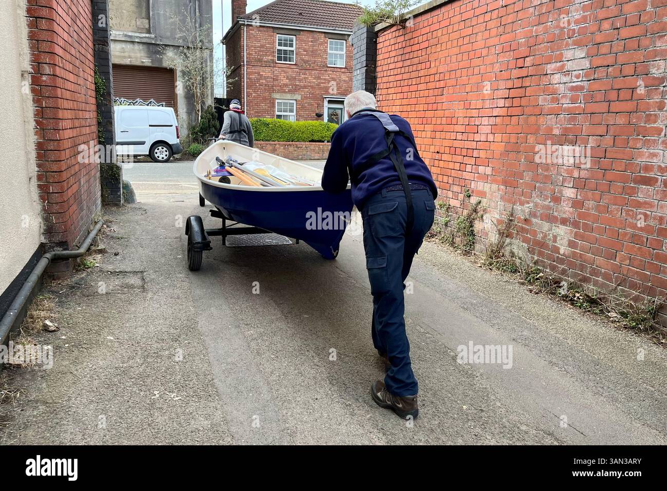 Two gentleman hauling a rowing boat from Underfall Yard up the narrow path towards Avon Crescent. Bristol, England, United Kingdom. 26th March 2025. - Smartphone Captured Stock Image