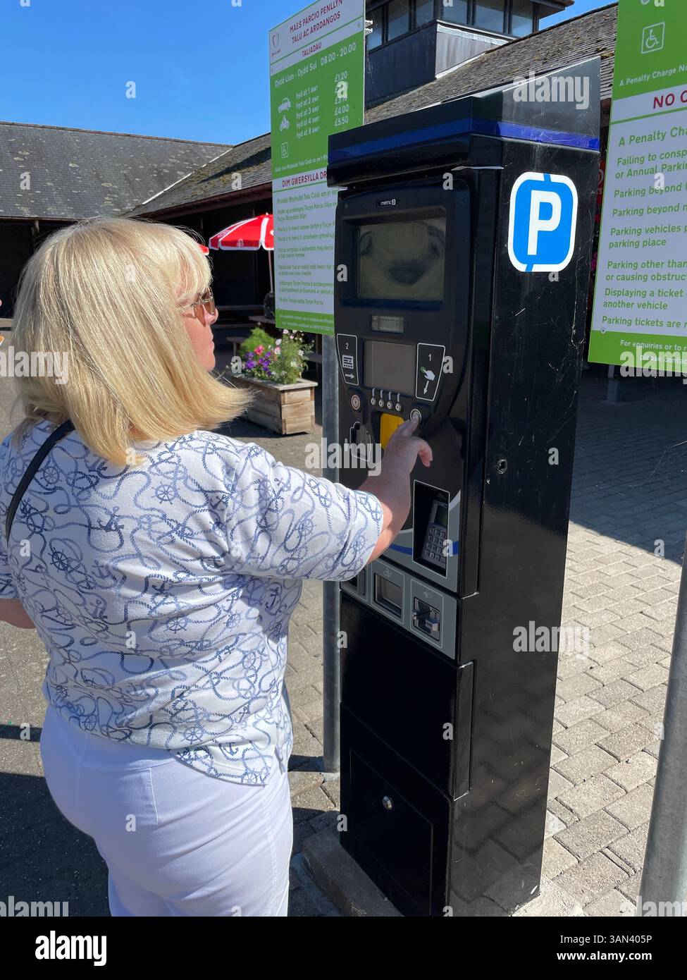 Mature woman motorist pays for parking in car park machine booth - Smartphone Captured Stock Image