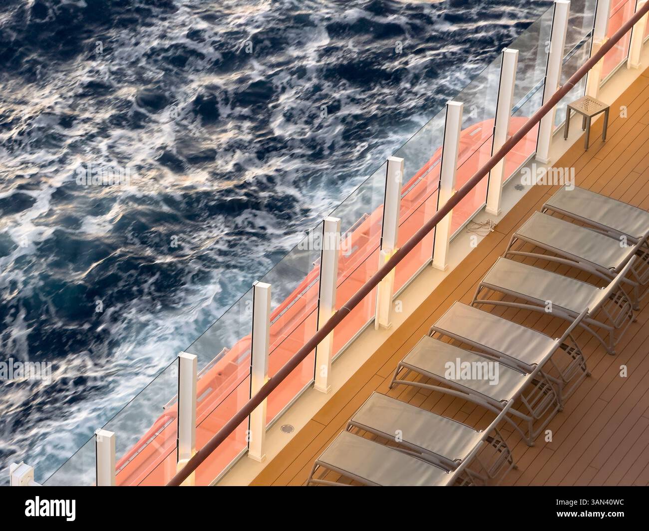 Sun loungers on cruise ship deck with sea and waves passing by, sunset - Smartphone Captured Stock Image